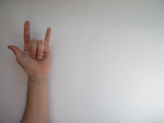 Female hand shows a gesture of rock horns on white background