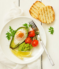 Fried eggs in avocado with guacamole sauce. Breakfast. Selective focus