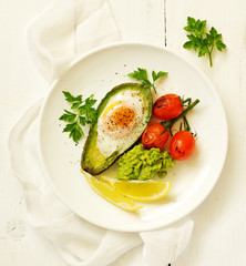 Fried eggs in avocado with guacamole sauce. Breakfast. Selective focus