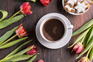 Fototapeta na wymiar Beautiful spring tulip flowers , a cup of coffee and cakes on rustic wooden background. Flat lay.