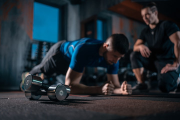 young man has workout with personal trainer in modern gym