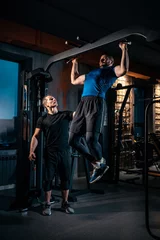 Schilderijen op glas young man has workout with personal trainer in modern gym © goami