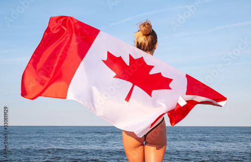 National Flag of Canada. Beautiful woman with canadian flag on the beach.