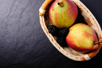 Pears in a wooden basket on a dark background