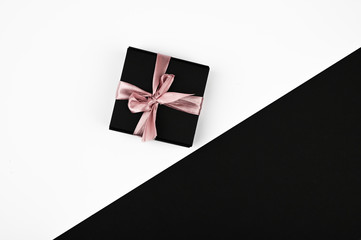 Black-white gifts. Colored ribbon wound on a black gift box. sleek layout, top view.