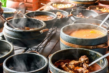 Typical Brazilian foods placed in clay pots and on a metal plate of a traditional wood stove