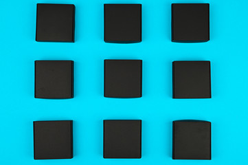 black boxes on blue. black boxes on a blue background on a flat lay. Black square on blue. black cubes flow