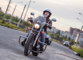 Woman motorcyclist riding on her chopper motorcycle on road