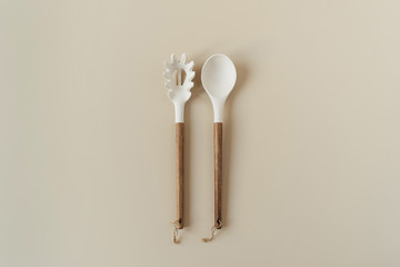 Salad serving utensils set. Wooden spoon and fork on neutral beige background. Minimal kitchenware concept.