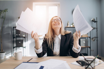 Mature blonde woman in business suit and eyeglasses feeling stress because of long paper work at office center. Concept of business and working process.