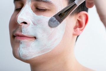 Man with a mask on his face. Applying the mask with a brush on the face. Cosmetics for men....