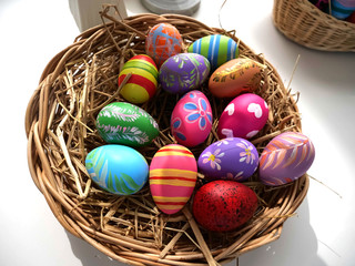 Fototapeta na wymiar Easter eggs, in a wooden basket in various colors, isolated on a white background