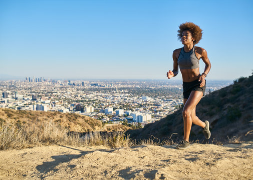 fit african american woman running at runyon canyon with los angeles in background