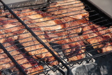 A large steak of grilled meat with smoke. Cooking in the open air.