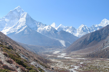White snowy Ama Dablam mountain peak rises above mountain valley in Himalayas in the morning on the...