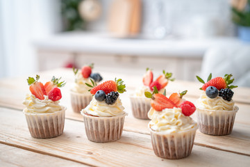 Fresh, delicious cupcakes with yogurt cream and fresh berries. Blur background.