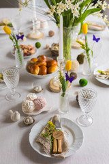 Easter festive spring table setting decoration, eggs in nest, fresh yellow tulips, marshmallows, selective focus