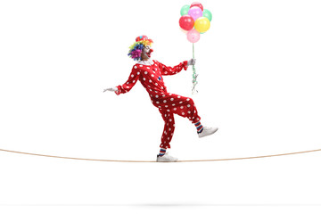 Clown walking on a rope and holding a bunch of balloons
