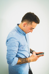 sesion de interior a un chico joven elegante y trajeado con tatuajes en el brazo, haciendo poses, mirando a la c&aacute;mara, al m&oacute;vil y en  varias poses