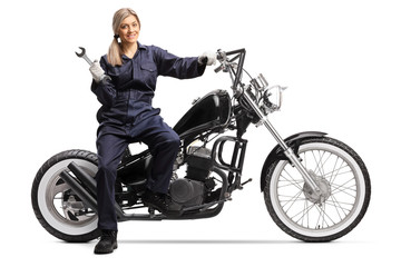 Female mechanic in a ubiform sitting on a motorbike