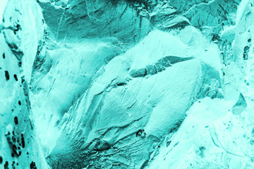 Vintage azure background. Rough painted wall of turquoise color. Imperfect plane of cyan colored. Uneven old decorative toned backdrop of aqzure tint. Texture of teal hue. Ornamental stony surface.