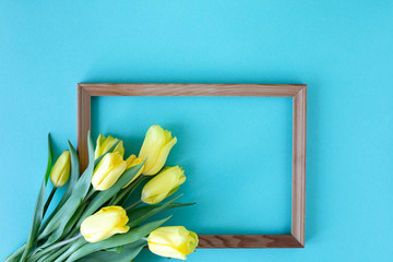 Beautiful flower arrangement. Yellow flowers tulips, empty frame for text on a blue background. Wedding. Birthday Valentine's Day. Mothers Day. Flat lay, top view, copy space