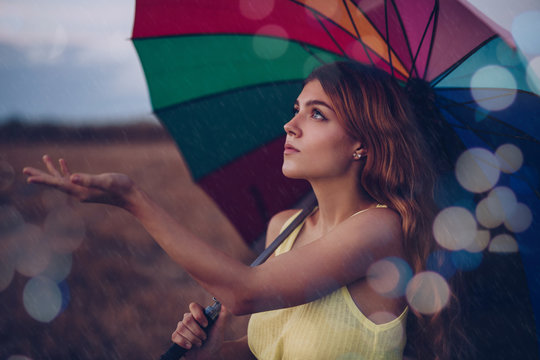 Young Woman Catching Raindrops In Field