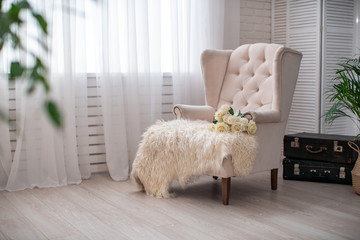 white chair, English- style against a white wall, and large window with curtain.