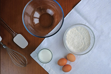 cooking pancakes on wooden background top view. Ingredients for making dough. Eggs, flour, milk.