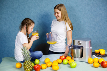 Little girl and mom squeeze fresh juice from fruits and drink it.
