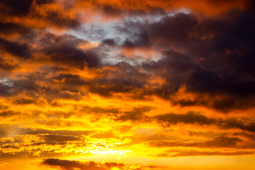 Fototapeta premium Fiery orange sunset sky with light and clouds.