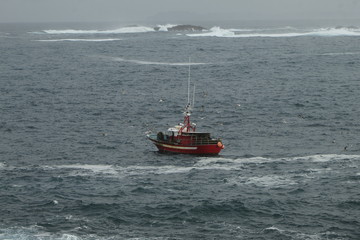 Small fishing boat, fishing near the coast, in bad weather, in La Coruña, Spain