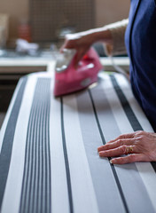 Woman ironing with steam iron. Selective focus on foreground