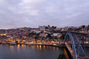 Fototapeta na wymiar Porto, Portugal - 09/25/2019: Porto view, with Dom Luís Bridge and metro. Sunset, blue sky and clouds. Boats on the river