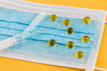 Medical protective mask with syringes on a yellow background. Corona virus. Healthcare and medical...