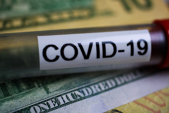 Corona virus covid-19 uncertain consequential costs concept symbol: macro closeup of isolated blood sample vial on 100 us dollar paper bank note