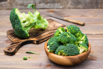 Ready to eat fresh raw broccoli is divided into inflorescences in a wooden plate and on a cutting...