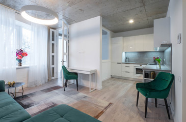 Modern interior of living room and kitchen in new studio apartment. Green furniture. White kitchen.