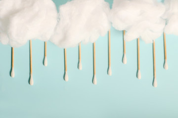Rain from wooden ear sticks.Natural Cotton Buds For Eye Cleaning.Blue backdrop.Cotton clouds.