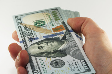 Stack of american money in hand, one hundred dollar cash banknotes on white background, lot of one hundred dollar bills