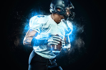 American football player in helmet with ball in hands. Fire background. Team sports. Sport...