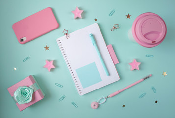 Flat layout of notepad with turquoise and pink accessories