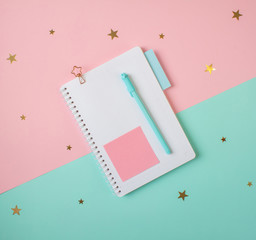 Flat layout of blank notepad with pen and stickers on colorful background with golden stars