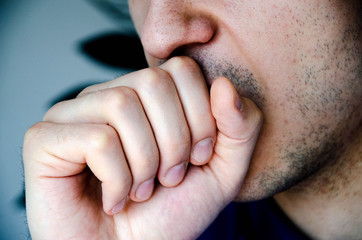 Fototapeta premium A man in close-up coughs in his hand, fist. Cough. Virus infection. Man with stubble. COVID-19