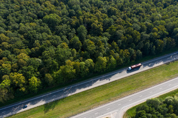 The truck is in a hurry to deliver the cargo, driving along a straight highway laid through the...