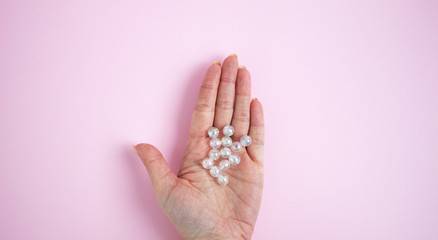 Hand with glass beads on the palm on a pink background