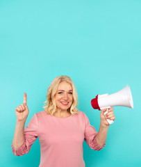 Cute blond mid woman speak in the megaphone isolated over the blue background