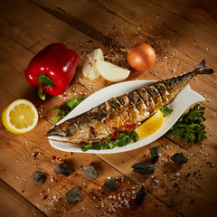 Appetizing grilled fish with vegetables on wooden background. Homemade smoked mackerel fish....