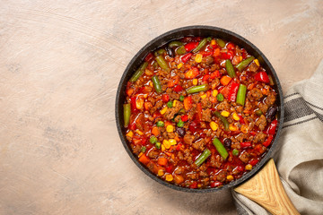Chili con carne in skillet on light stone table.