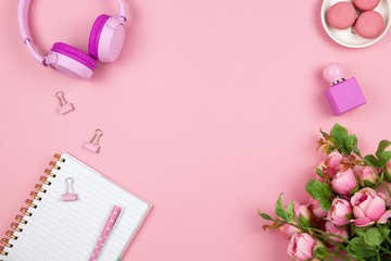 Modern female working space, top view. Women's or girls things, wireless headphones, roses, perfume, stationery on pink backround, copy space, flat lay. Work from home concept. For blog. Horizontal